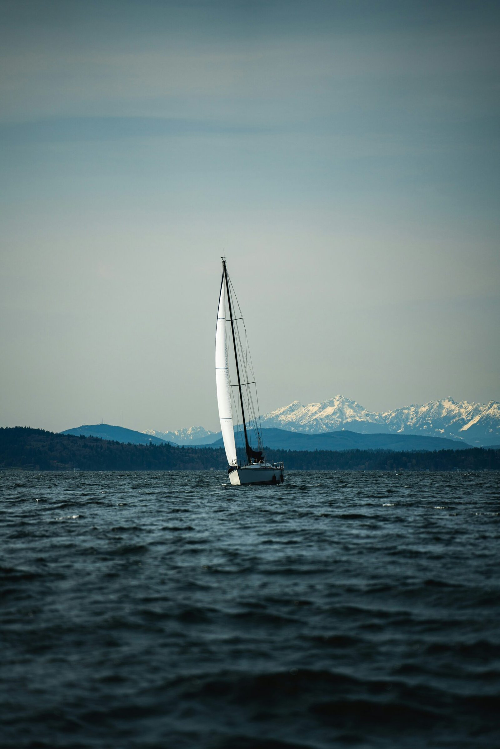 a sailboat in the ocean with mountains in the background